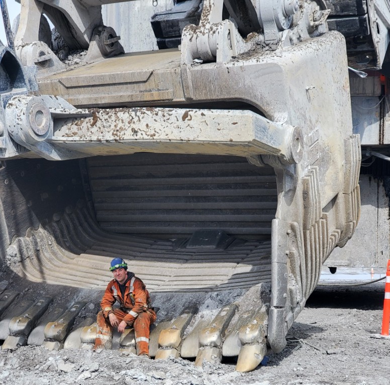 Worker with massive excavator bucket showing scale of heavy equipment we service